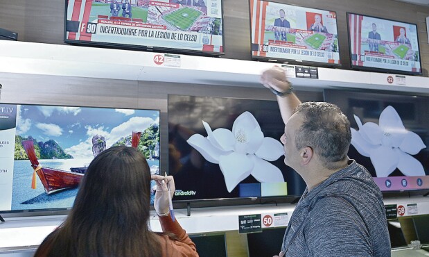 Personas de compras en tienda de electrodomésticos, televisores