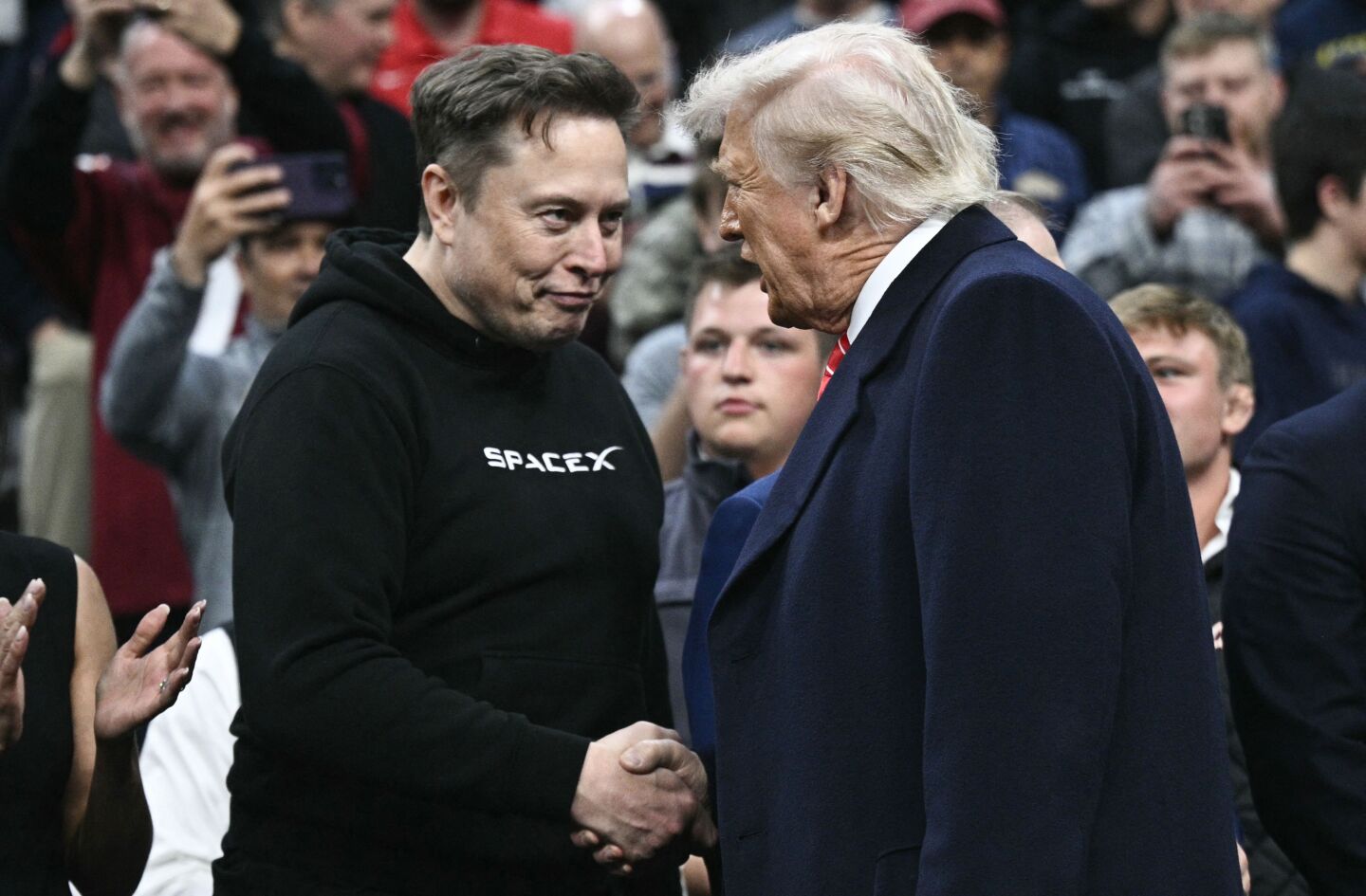 Elon Musk, director ejecutivo de Tesla y SpaceX, y el presidente de Estados Unidos, Donald Trump, se dan la mano mientras asisten a la competencia de lucha libre masculina de la NCAA.