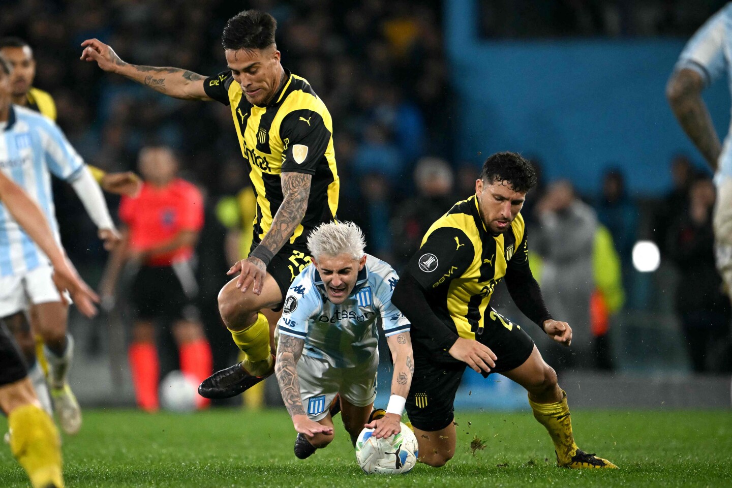 Javier Méndez y Eric Remedi marcan a Gastón Martirena en el partido entre Racing y Peñarol.