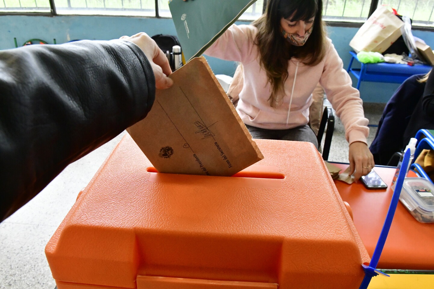 Una persona introduciendo un voto a una urna electoral.