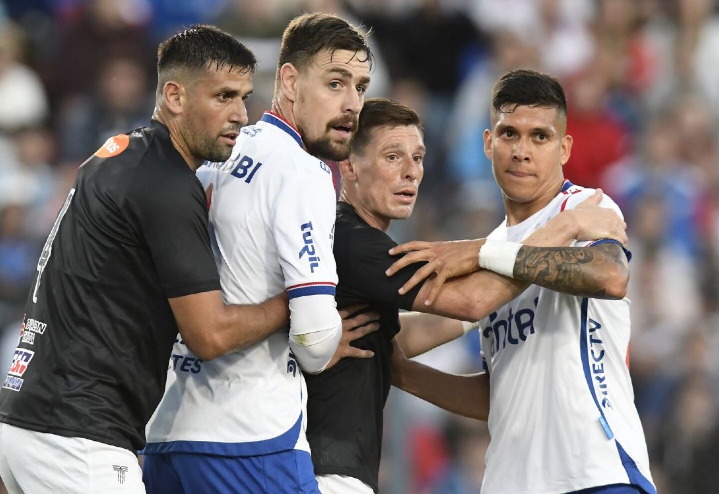 Sebastián Coates y Julián Millán son marcados por Mario Risso y Santiago Romero en el partido entre Nacional y Danubio.
